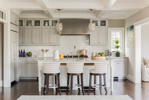 Transitional kitchen featuring white RTA cabinets, subway tile backsplash, stainless range hood, and a marble island with three stools.