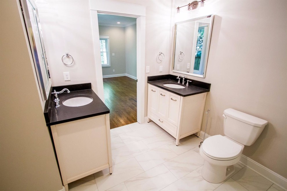 This is an example of a mid-sized traditional 3/4 bathroom in Other with shaker cabinets, white cabinets, a corner shower, a two-piece toilet, white tile, porcelain tile, white walls, marble floors, an undermount sink, granite benchtops, white floor and a hinged shower door.