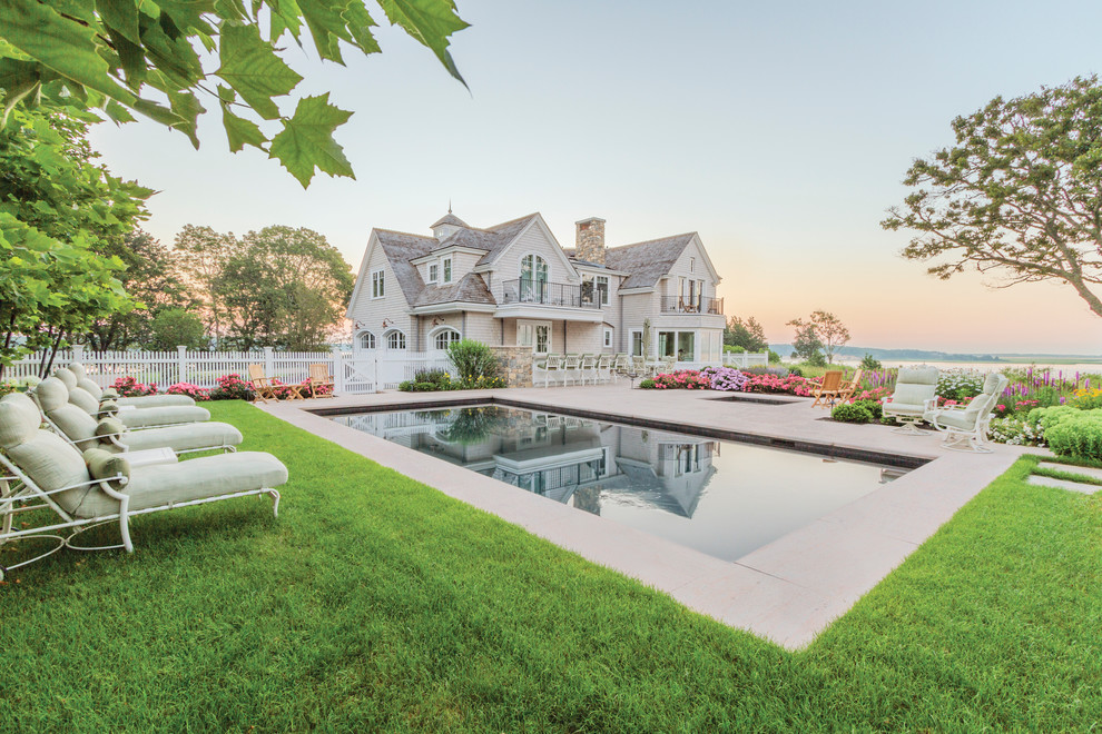 This is an example of an expansive traditional backyard rectangular pool in Boston with natural stone pavers.