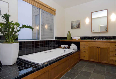 This is an example of a modern bathroom in San Francisco with flat-panel cabinets, light wood cabinets, an undermount tub, a curbless shower, black tile, terra-cotta tile, white walls, slate floors, an undermount sink and tile benchtops.
