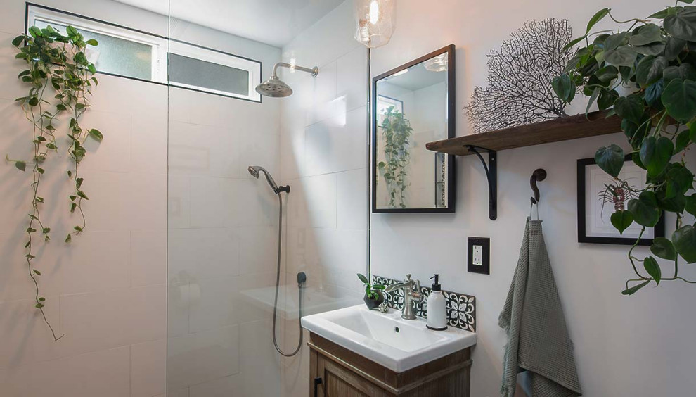 Mid-sized beach style black and white tile and porcelain tile pebble tile floor, gray floor and single-sink bathroom photo in Los Angeles with shaker cabinets, distressed cabinets, a one-piece toilet, white walls, a pedestal sink, solid surface countertops, white countertops, a niche and a freestanding vanity