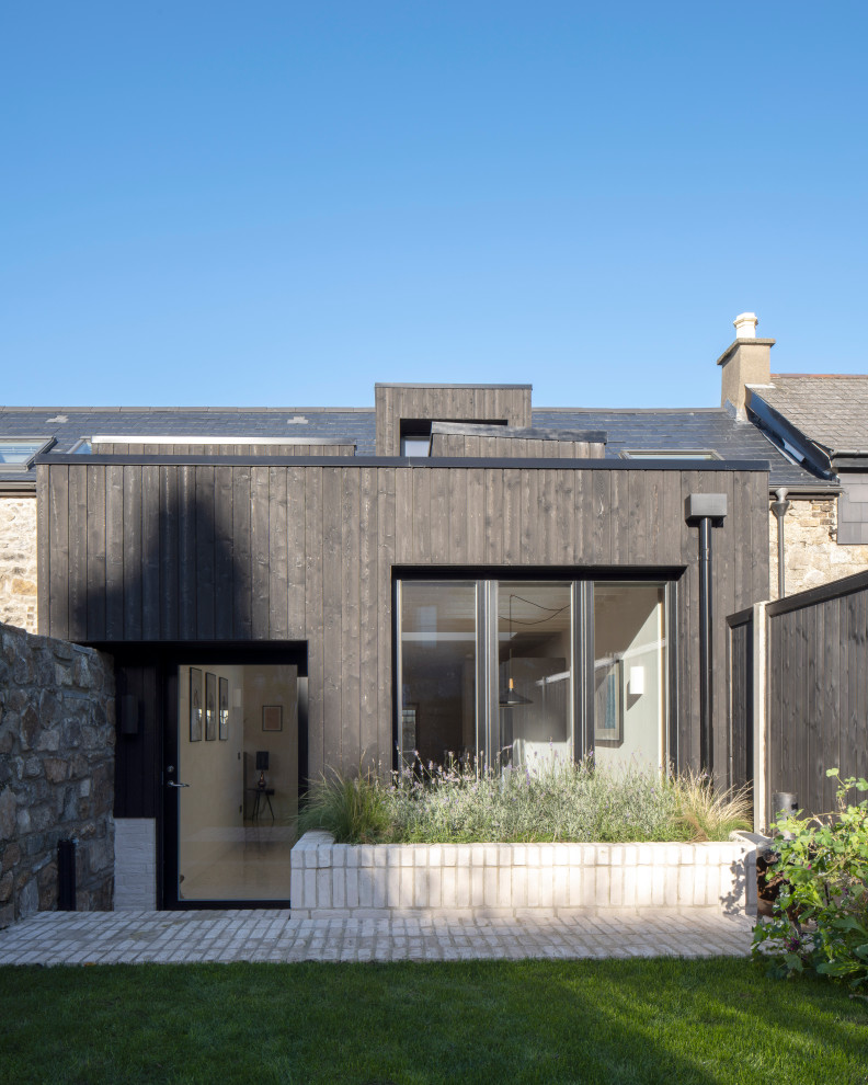 Ejemplo de fachada de casa pareada negra y negra contemporánea de tamaño medio de dos plantas con revestimiento de madera, tejado a dos aguas, tejado de teja de barro y panel y listón