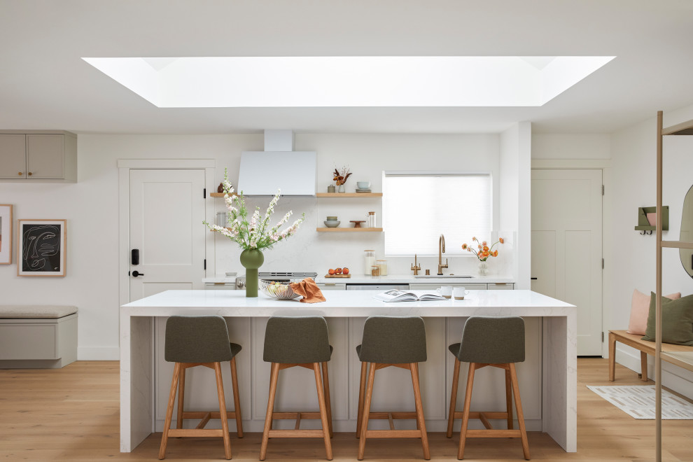 Exempel på ett mellanstort nordiskt vit linjärt vitt kök med öppen planlösning, med en undermonterad diskho, skåp i shakerstil, grå skåp, bänkskiva i kvarts, vitt stänkskydd, rostfria vitvaror, ljust trägolv, en köksö och brunt golv