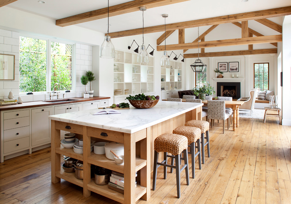 Photo of a country open plan kitchen in San Francisco with an undermount sink, open cabinets, white cabinets, white splashback, subway tile splashback, medium hardwood floors and with island.