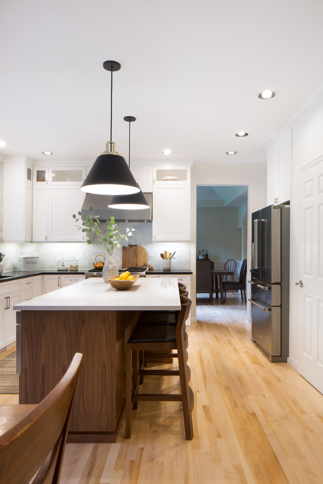 Inspiration for a mid-sized transitional l-shaped light wood floor and brown floor eat-in kitchen remodel in Seattle with an undermount sink, shaker cabinets, white cabinets, quartz countertops, multicolored backsplash, marble backsplash, stainless steel appliances and an island