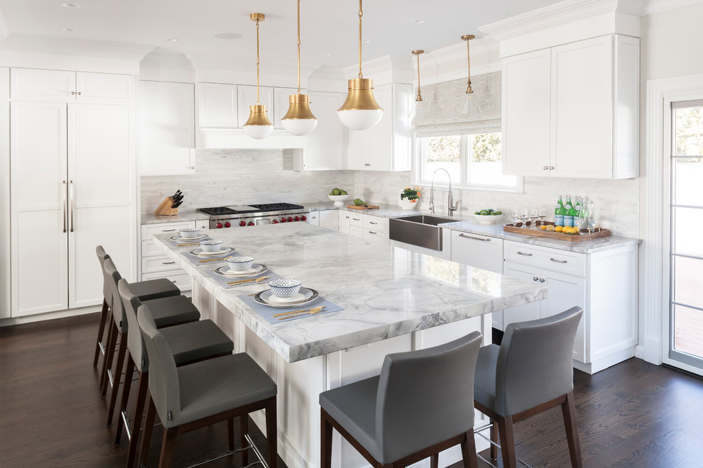 This is an example of a large transitional l-shaped eat-in kitchen in New York with a farmhouse sink, shaker cabinets, white cabinets, quartzite benchtops, white splashback, marble splashback, dark hardwood floors, with island and stainless steel appliances.