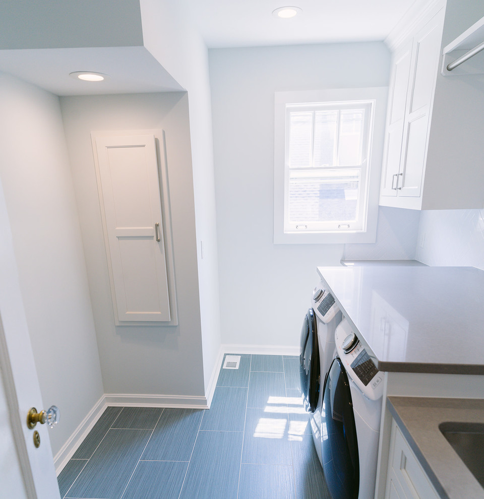 Design ideas for a mid-sized transitional galley dedicated laundry room in Cincinnati with a single-bowl sink, white cabinets, quartz benchtops, white walls, ceramic floors, an integrated washer and dryer, grey floor, recessed-panel cabinets and grey benchtop.