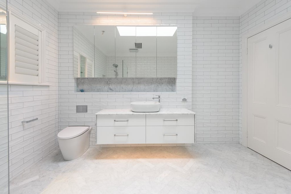 Photo of a large traditional bathroom in Melbourne with flat-panel cabinets, white cabinets, a claw-foot tub, a one-piece toilet, white tile, ceramic tile, white walls, marble floors, a vessel sink, marble benchtops and multi-coloured floor.