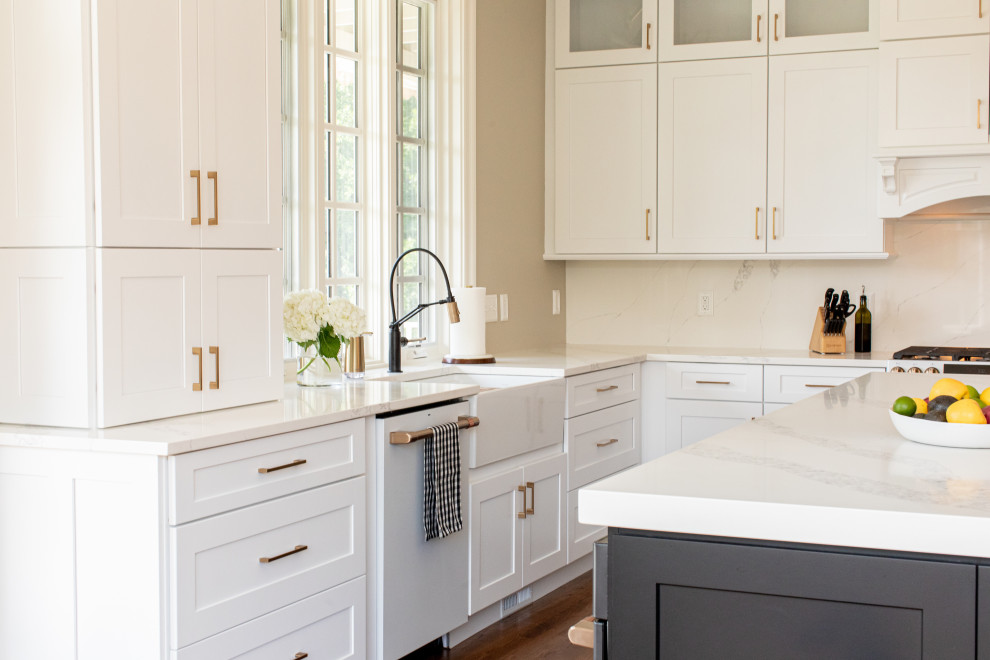 Transitional kitchen in Baltimore with a farmhouse sink, shaker cabinets, white cabinets, white splashback, white appliances, medium hardwood floors, with island and white benchtop.