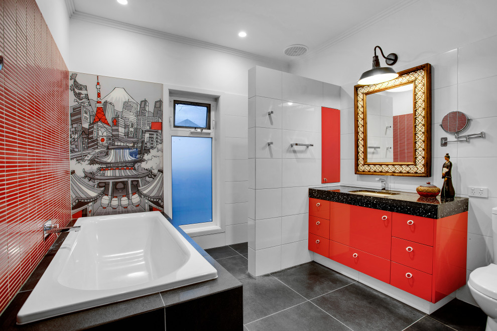 На фото: большая главная ванная комната в стиле фьюжн с плоскими фасадами, красными фасадами, накладной ванной, душем в нише, унитазом-моноблоком, белой плиткой, керамогранитной плиткой, красными стенами, полом из керамической плитки, врезной раковиной, столешницей из искусственного кварца, черным полом, открытым душем, черной столешницей, нишей, тумбой под одну раковину и встроенной тумбой