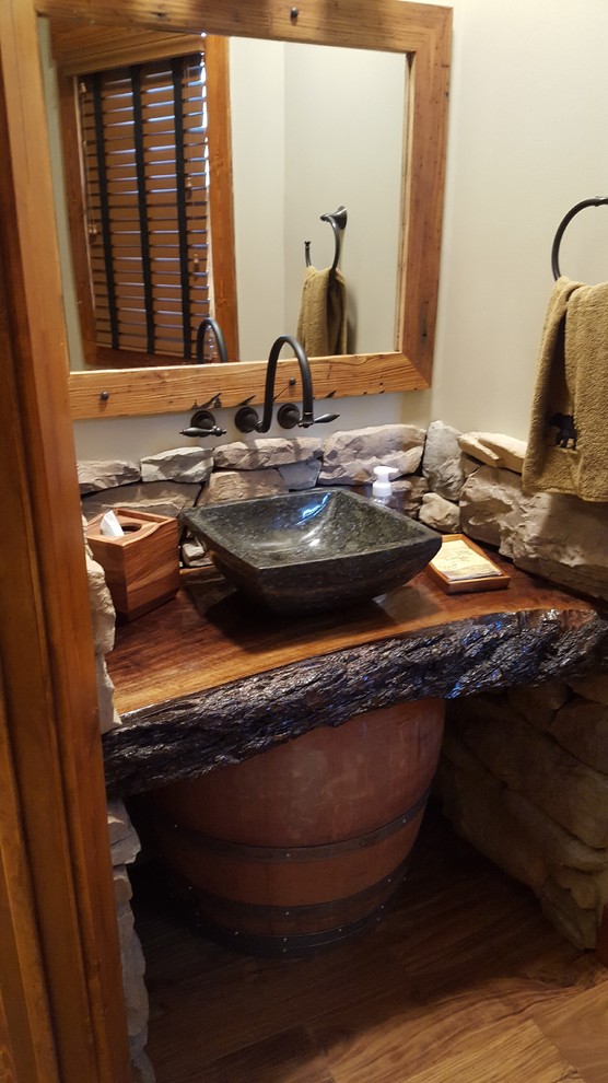 Inspiration for a mid-sized country powder room in Other with wood benchtops, raised-panel cabinets, black cabinets and light hardwood floors.