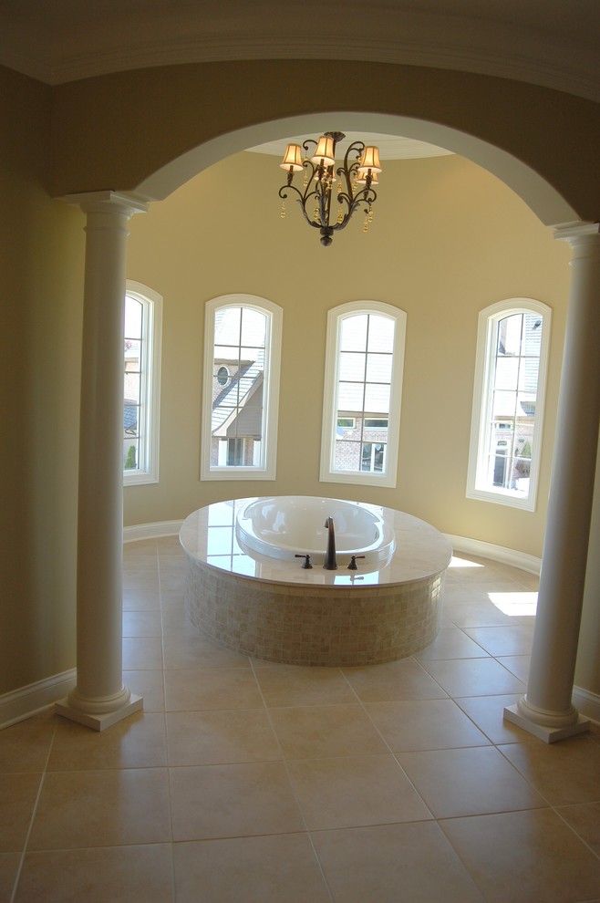This is an example of a mediterranean bathroom in Chicago with a drop-in tub, beige tile and stone tile.