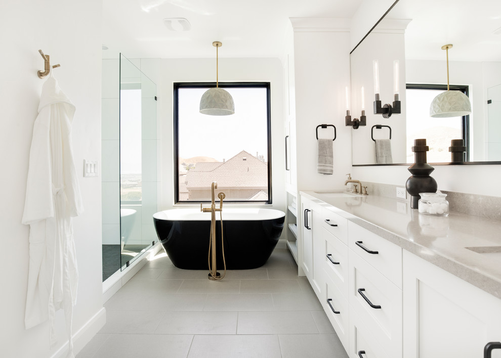 Mid-sized transitional master bathroom in Salt Lake City with shaker cabinets, white cabinets, a freestanding tub, an alcove shower, white tile, ceramic tile, white walls, ceramic floors, an undermount sink, grey floor and grey benchtops.