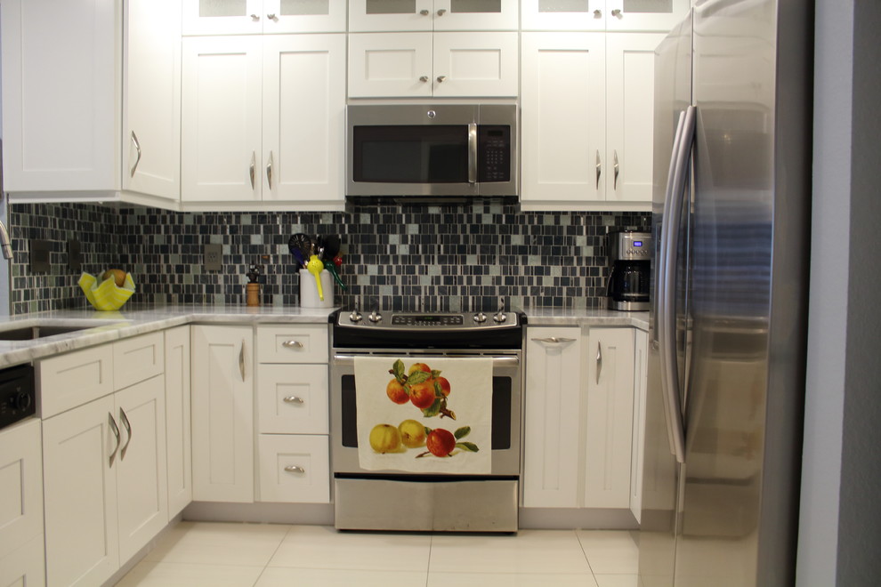 Enclosed kitchen - mid-sized transitional u-shaped porcelain tile and white floor enclosed kitchen idea in Miami with an undermount sink, shaker cabinets, white cabinets, quartzite countertops, gray backsplash, glass tile backsplash, stainless steel appliances and no island