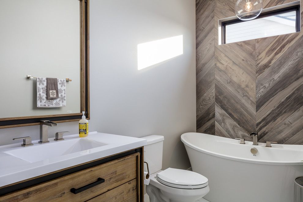 Transitional bathroom in Other with flat-panel cabinets, medium wood cabinets, a freestanding tub, a two-piece toilet, brown tile, white walls, a drop-in sink and white benchtops.