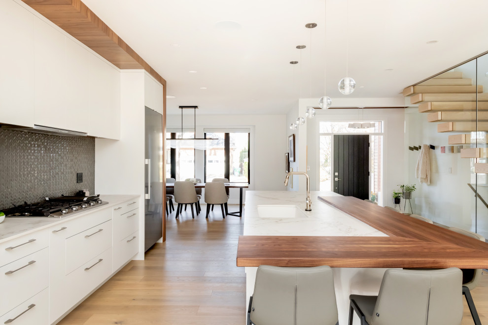 Idéer för ett mellanstort modernt grå linjärt kök med öppen planlösning, med en undermonterad diskho, släta luckor, vita skåp, bänkskiva i kvarts, grått stänkskydd, stänkskydd i porslinskakel, rostfria vitvaror, ljust trägolv och beiget golv