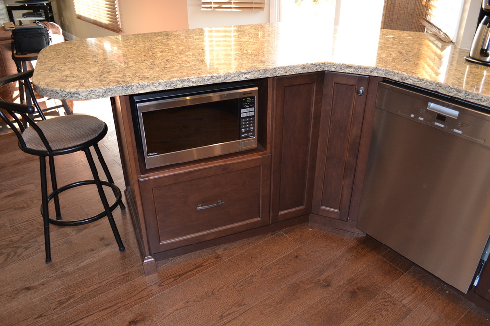 Mid-sized transitional u-shaped medium tone wood floor kitchen pantry photo in Toronto with an undermount sink, recessed-panel cabinets, medium tone wood cabinets, quartz countertops, beige backsplash, glass sheet backsplash, stainless steel appliances and a peninsula
