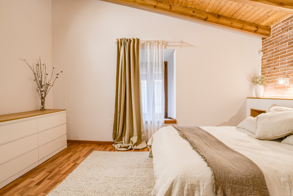 Ejemplo de dormitorio principal y blanco y madera bohemio de tamaño medio con paredes blancas, suelo de madera en tonos medios, madera y ladrillo