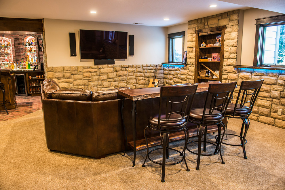 This is an example of a large country look-out basement in Kansas City with beige walls, a corner fireplace, a brick fireplace surround, carpet and beige floor.