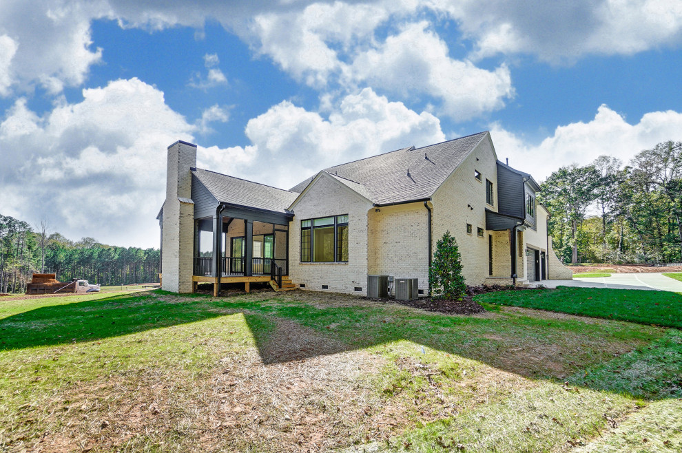 Großes, Zweistöckiges Einfamilienhaus mit gestrichenen Ziegeln, weißer Fassadenfarbe, Satteldach, Schindeldach, schwarzem Dach und Wandpaneelen in Charlotte