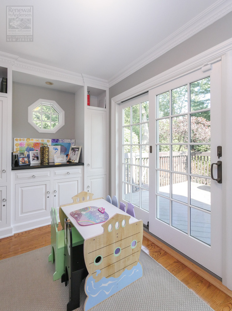 Foto på ett litet könsneutralt barnrum kombinerat med lekrum och för 4-10-åringar, med grå väggar, mellanmörkt trägolv och flerfärgat golv
