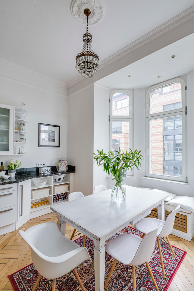 This is an example of a large scandinavian single-wall eat-in kitchen in Cologne with flat-panel cabinets, white cabinets, light hardwood floors, granite benchtops and no island.