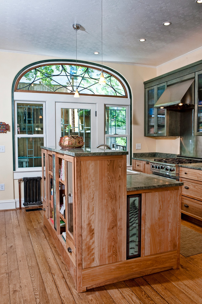 Inspiration for a small transitional l-shaped medium tone wood floor eat-in kitchen remodel in DC Metro with granite countertops, an island, a drop-in sink, glass-front cabinets, green cabinets, metallic backsplash, metal backsplash and stainless steel appliances
