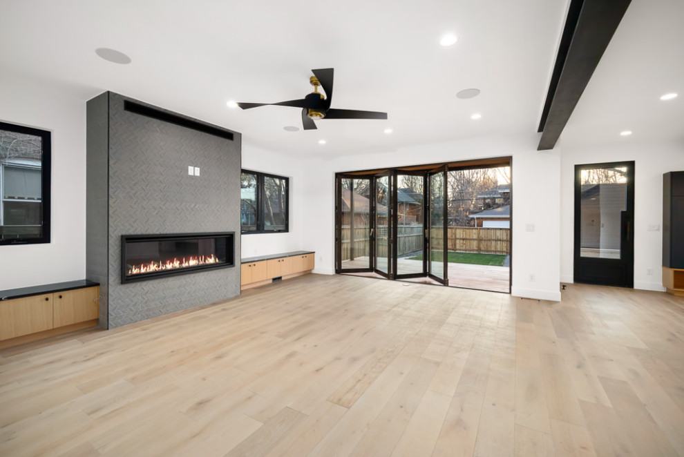 Inspiration for a large urban open plan living room in Denver with white walls, light hardwood flooring, a standard fireplace, a tiled fireplace surround, brown floors and exposed beams.