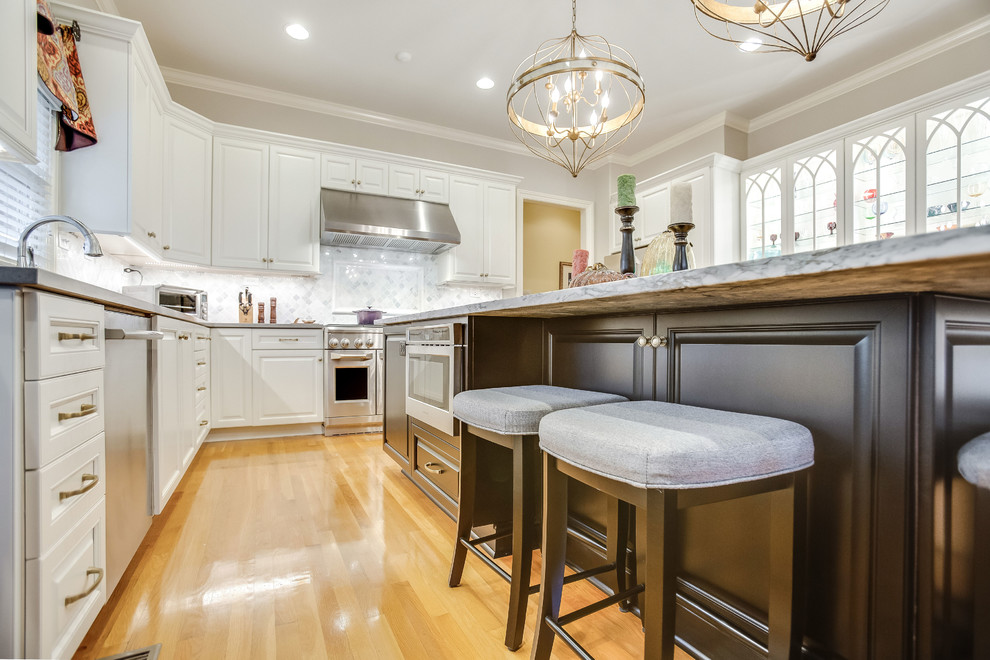 Open concept kitchen - large transitional u-shaped light wood floor and yellow floor open concept kitchen idea in Birmingham with raised-panel cabinets, white cabinets, marble countertops, white backsplash, marble backsplash, stainless steel appliances, an island and white countertops