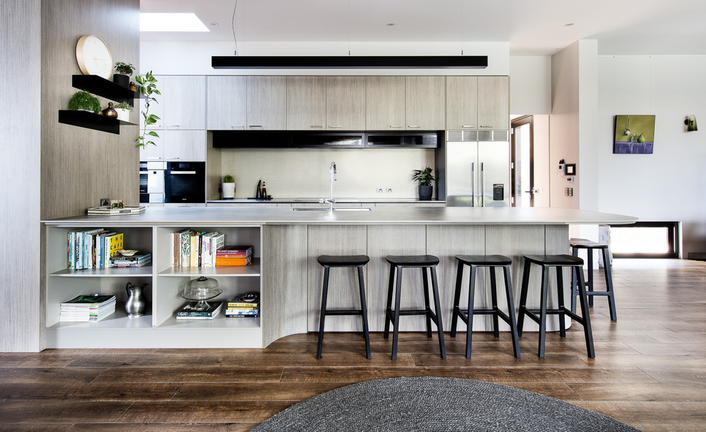 Photo of a large contemporary single-wall open plan kitchen in Melbourne with an undermount sink, flat-panel cabinets, grey cabinets, stainless steel appliances, medium hardwood floors, a peninsula and brown floor.