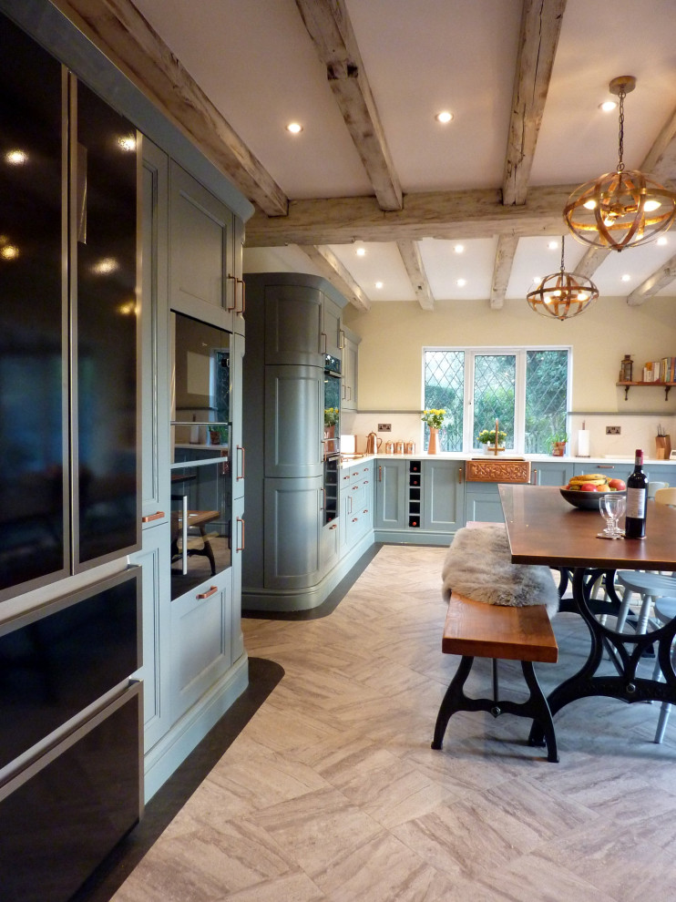 Photo of a large classic galley kitchen/diner in West Midlands with a belfast sink, beaded cabinets, blue cabinets, quartz worktops, orange splashback, black appliances, vinyl flooring, an island, grey floors, white worktops and exposed beams.