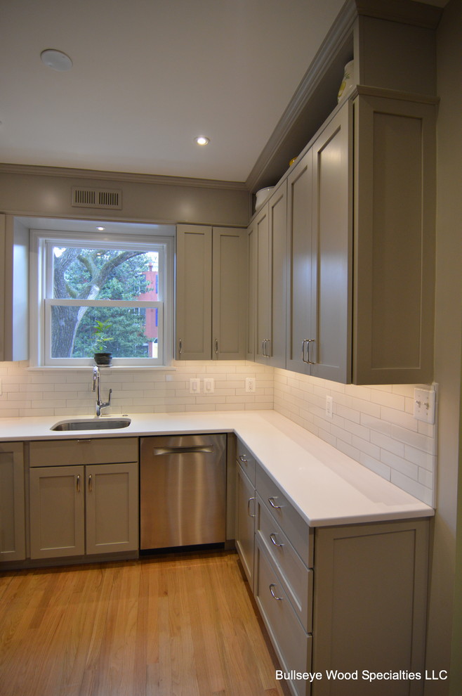 Inspiration for a small transitional u-shaped light wood floor enclosed kitchen remodel in DC Metro with an undermount sink, shaker cabinets, gray cabinets, quartz countertops, white backsplash, subway tile backsplash, stainless steel appliances and no island