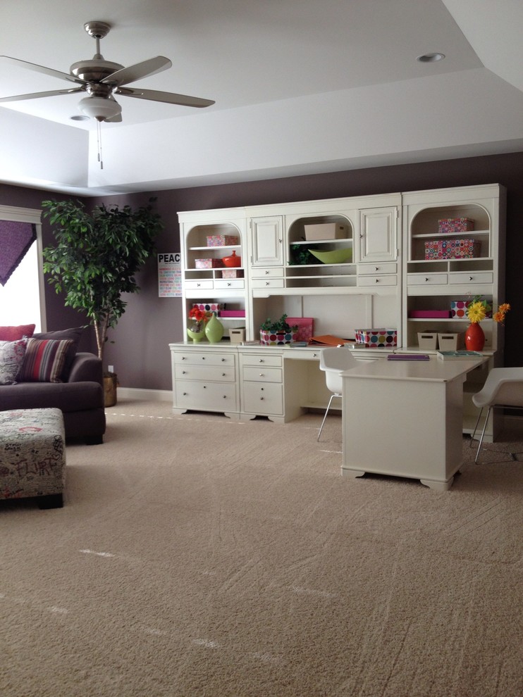 This is an example of a large transitional craft room in Cincinnati with purple walls, carpet and a built-in desk.