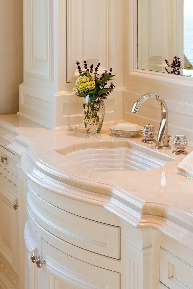 Expansive traditional master bathroom in Portland Maine with a drop-in sink, recessed-panel cabinets, white cabinets, marble benchtops, a drop-in tub and marble floors.