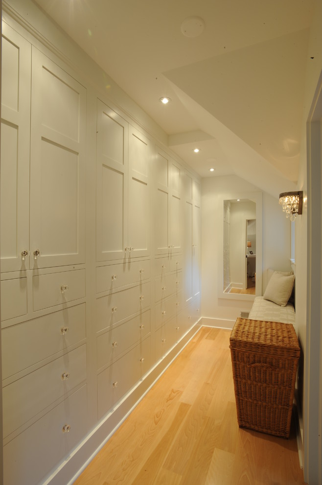 This is an example of a country walk-in wardrobe in Cleveland with shaker cabinets, white cabinets and light hardwood floors.