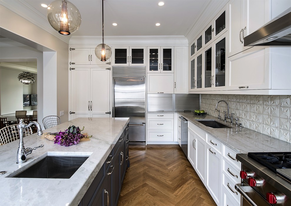 Example of a mid-sized transitional l-shaped medium tone wood floor open concept kitchen design in Chicago with an undermount sink, flat-panel cabinets, white cabinets, granite countertops, beige backsplash, stainless steel appliances, an island and mosaic tile backsplash