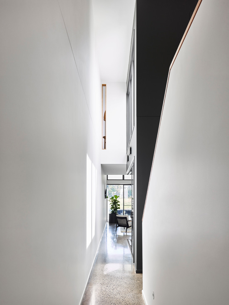 Photo of a mid-sized modern hallway in Sunshine Coast with white walls, concrete floors and grey floor.