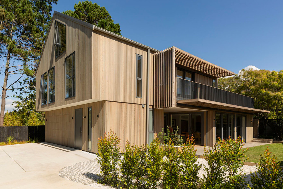 Inspiration for a large and brown contemporary side detached house in Auckland with three floors, wood cladding, a pitched roof, a metal roof, a black roof and board and batten cladding.