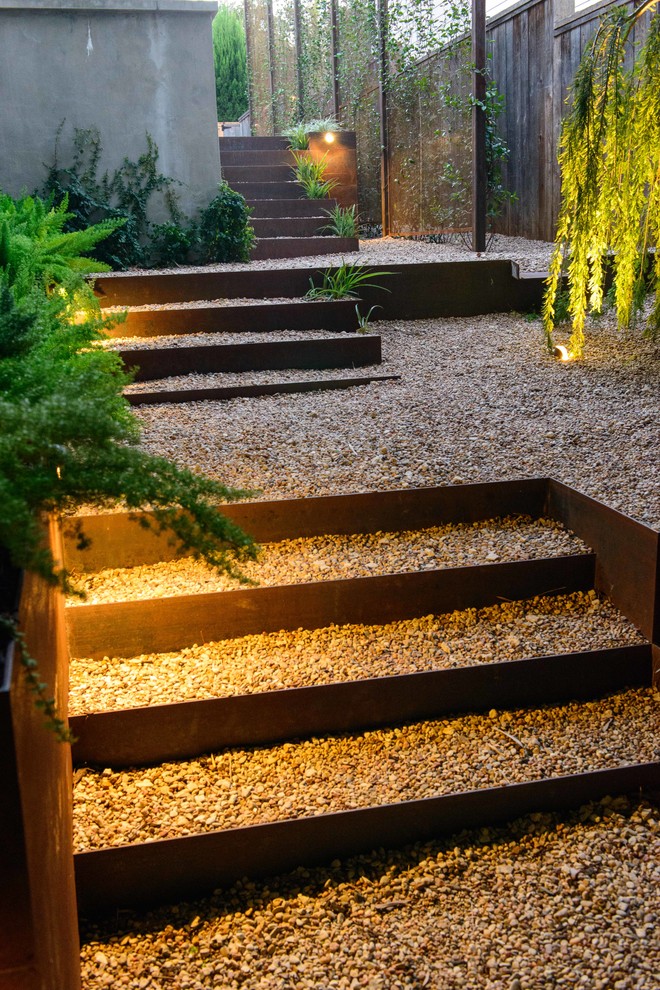 Design ideas for a mid-sized modern side yard partial sun formal garden for spring in Austin with gravel and a retaining wall.
