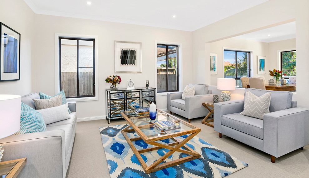 Mid-sized beach style open concept living room in Sydney with beige walls, light hardwood floors and a freestanding tv.