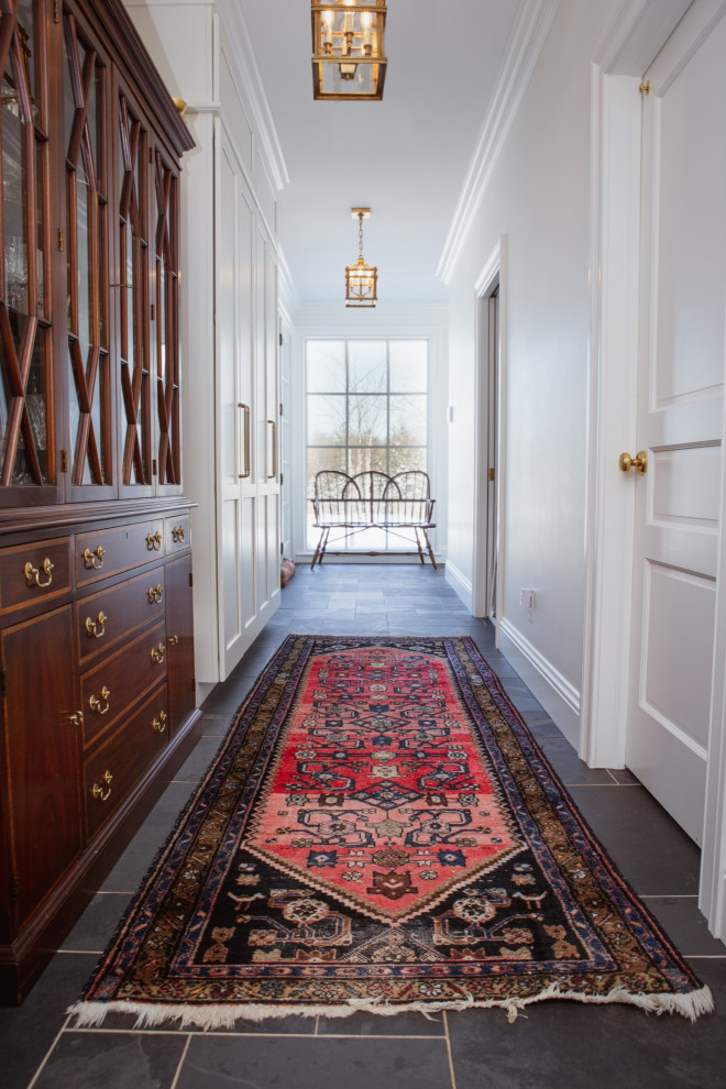This is an example of a traditional hallway in Chicago with white walls, slate floors and black floor.