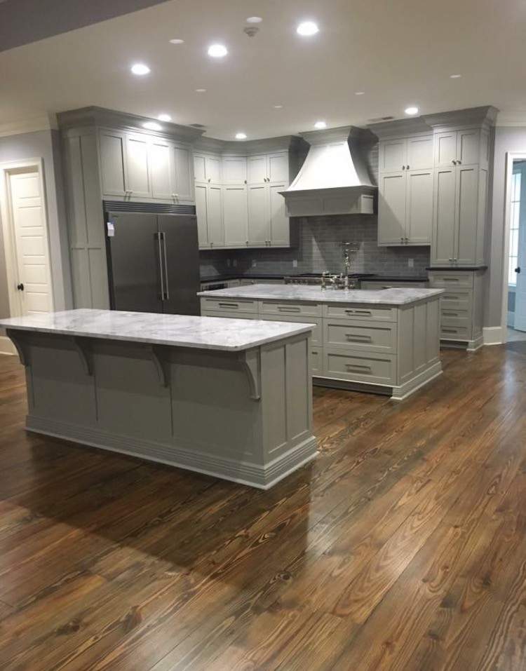 This is an example of a large transitional l-shaped open plan kitchen in Atlanta with a farmhouse sink, shaker cabinets, grey cabinets, marble benchtops, grey splashback, glass tile splashback, stainless steel appliances, medium hardwood floors, multiple islands and brown floor.