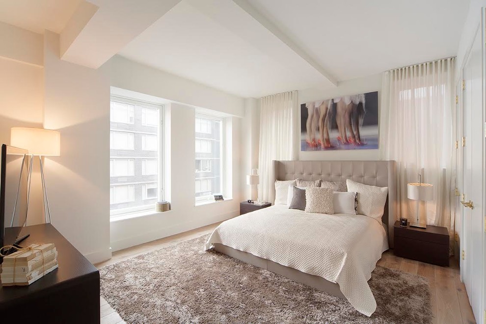 This is an example of a mid-sized contemporary guest bedroom in New York with white walls and medium hardwood floors.
