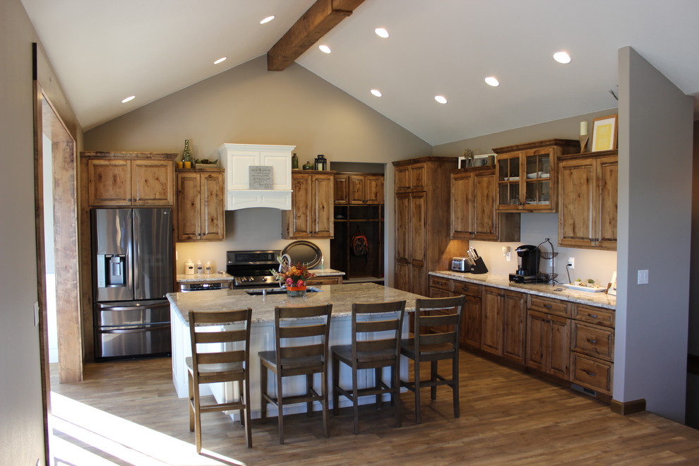 Open concept kitchen - large rustic l-shaped medium tone wood floor and brown floor open concept kitchen idea with an undermount sink, raised-panel cabinets, medium tone wood cabinets, granite countertops, stainless steel appliances and an island