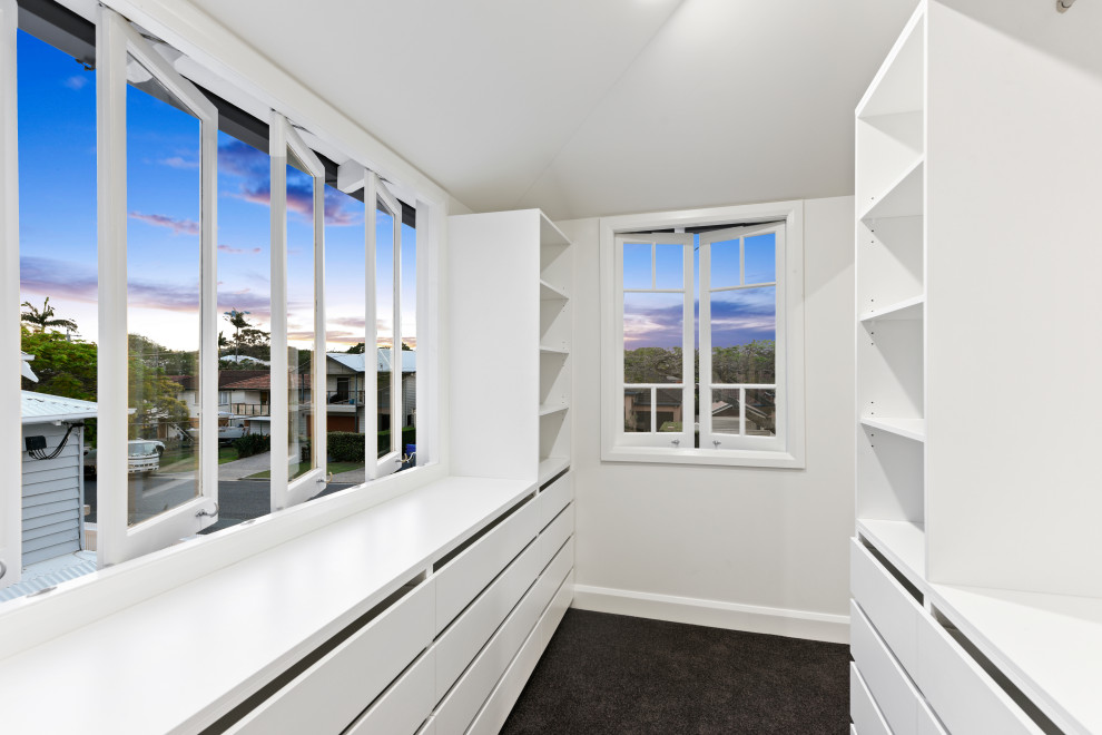 Photo of a mid-sized gender-neutral walk-in wardrobe in Brisbane with open cabinets, white cabinets, carpet and black floor.