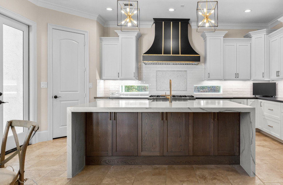 Inspiration for a large transitional l-shaped limestone floor and beige floor eat-in kitchen remodel in Houston with a farmhouse sink, recessed-panel cabinets, white cabinets, quartzite countertops, white backsplash, limestone backsplash, stainless steel appliances, an island and white countertops