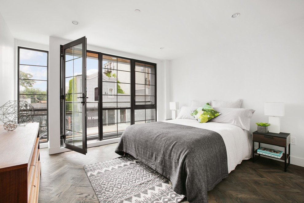 This is an example of a mid-sized contemporary bedroom in New York with white walls, dark hardwood floors and no fireplace.