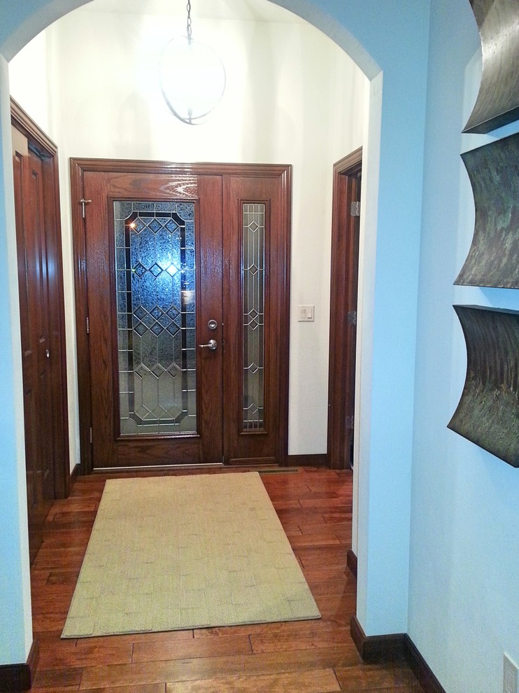 Example of a mid-sized transitional medium tone wood floor foyer design with blue walls and a medium wood front door
