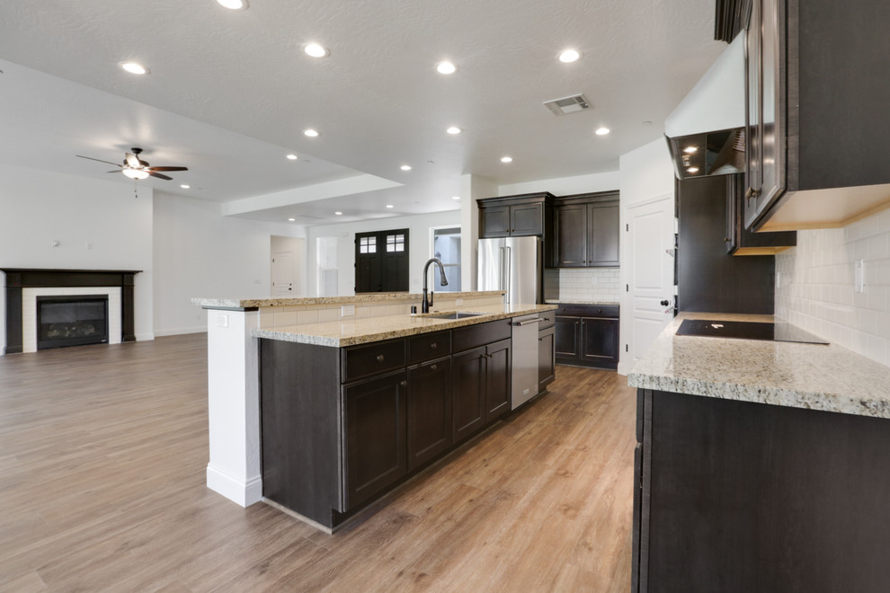 Inspiration for a laminate floor eat-in kitchen remodel with granite countertops, white backsplash, stainless steel appliances and an island