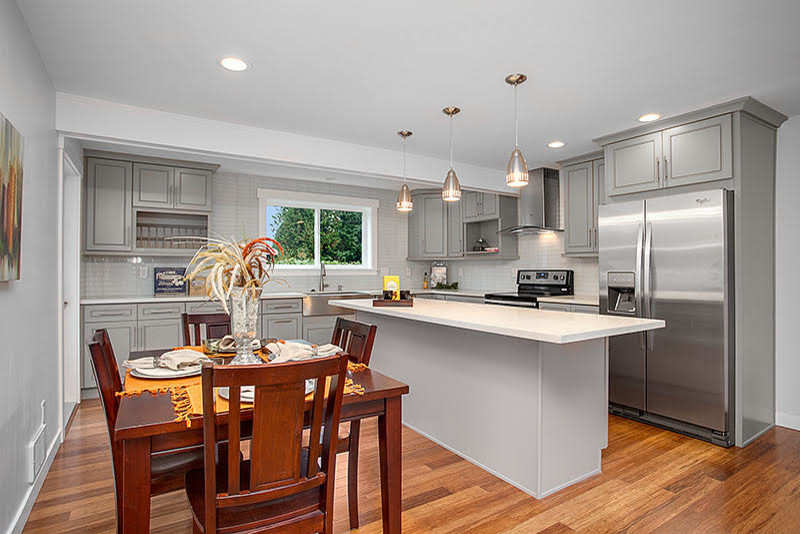Photo of a transitional eat-in kitchen in Seattle with raised-panel cabinets, grey cabinets, quartzite benchtops, white splashback, glass tile splashback, stainless steel appliances, medium hardwood floors and with island.